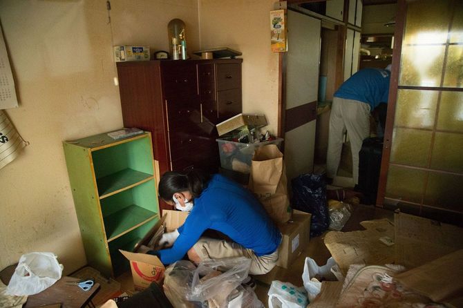 居室とダイニングに分かれ遺品整理する作業員