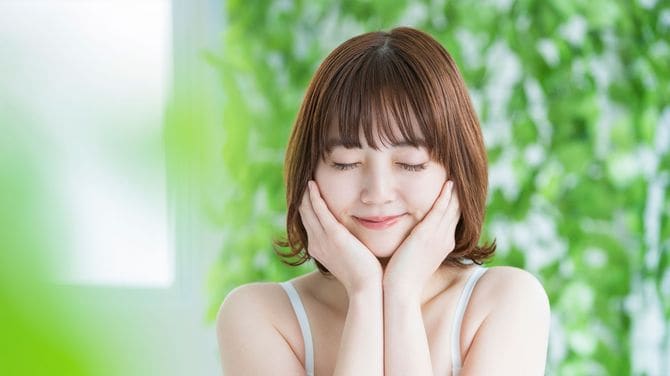 両手で頬を包み込み目を閉じている女性