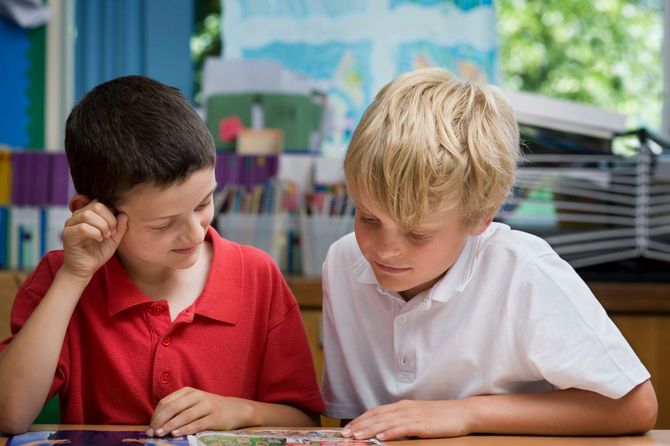 教室で隣の子と一緒に資料を見ている男の子たち