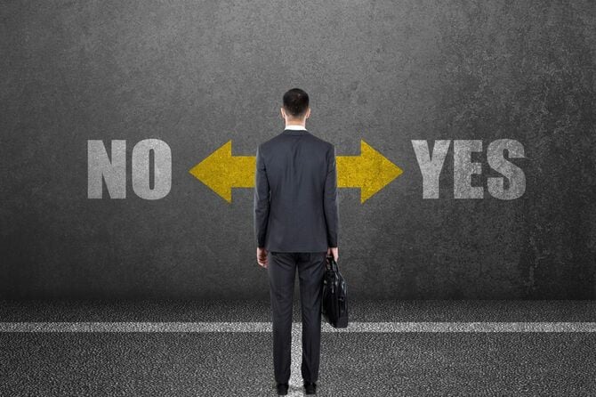 壁に書かれたイエス・ノーの文字と向き合うビジネスマン