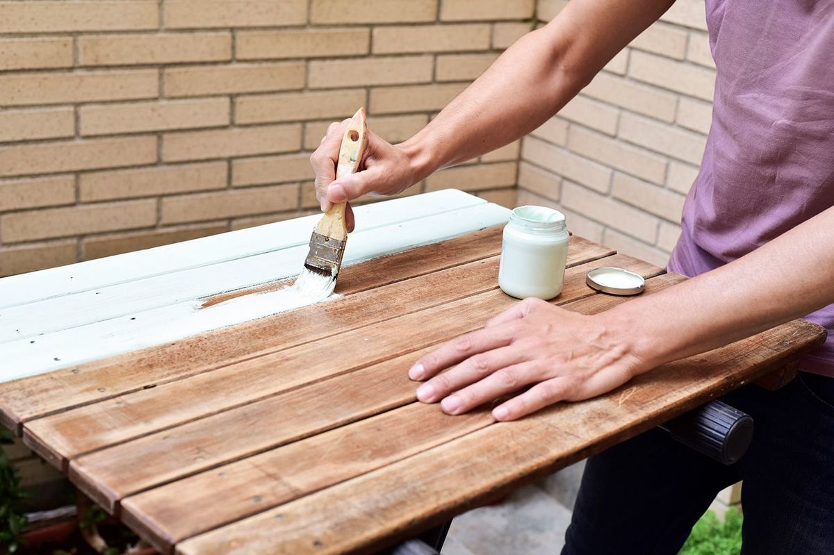 古い木製のテーブルを塗り替える人