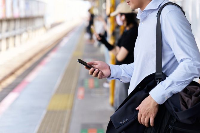電車を待つ間スマホを確認する人