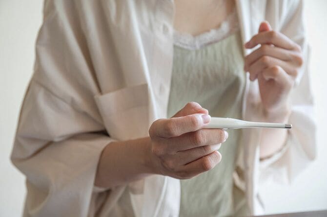 温度計で熱を測定する女性