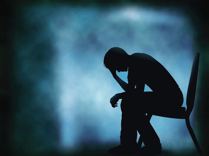 どんよりとした暗い空間で頭を抱えるうなだれる男性