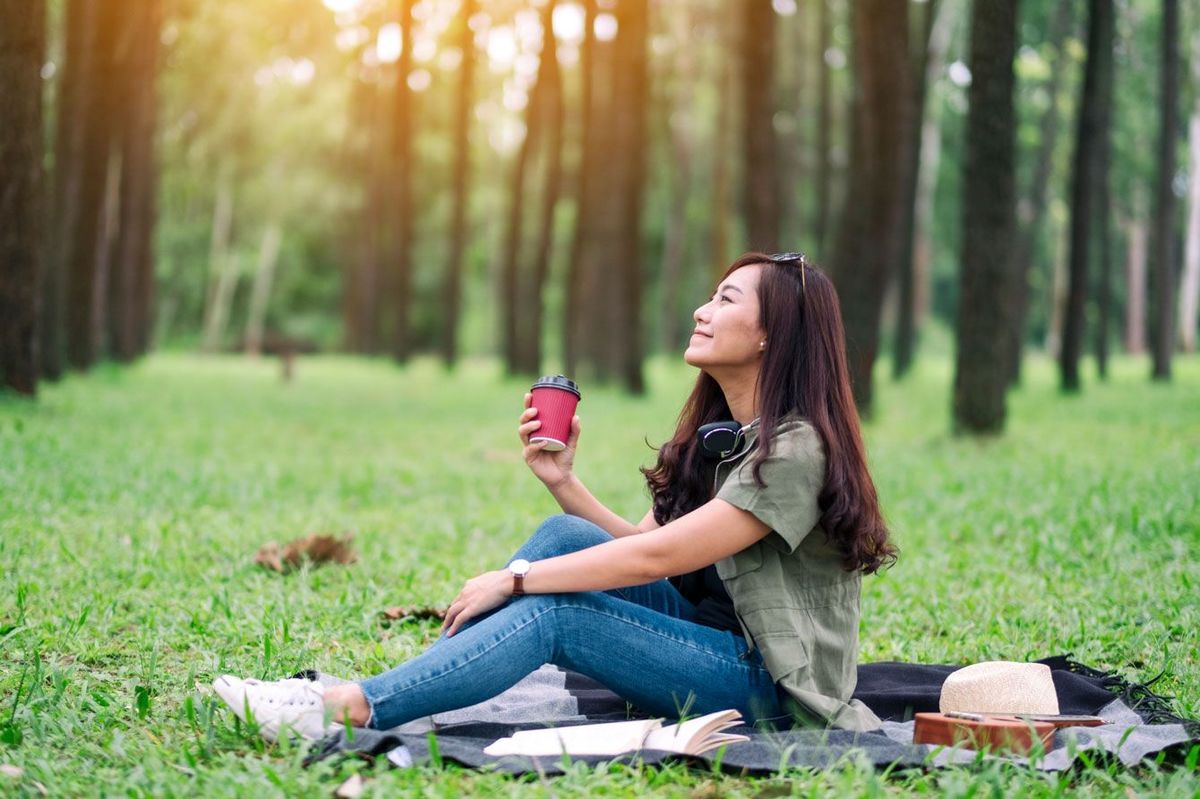 公園に座りながらコーヒーを飲む女性