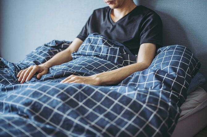寝室のベッドで起き上がっている男