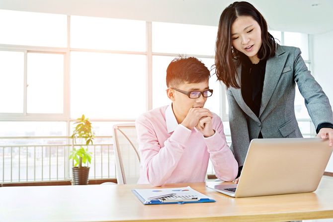 オフィスでパソコン画面を見ながら話をする二人