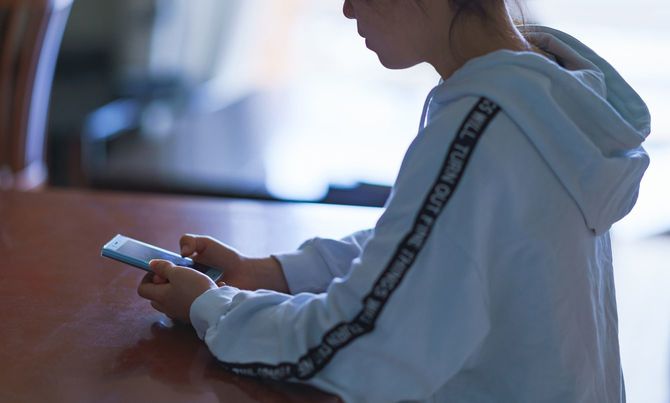 自宅でスマホを見つめる少女