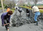 千葉県浦安市明海にて液状化現象で溜まった土を取り除くボランティア。埋め立て時期により被害に差が出た。(PANA=写真)