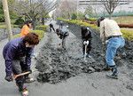 千葉県浦安市明海にて液状化現象で溜まった土を取り除くボランティア。埋め立て時期により被害に差が出た。(PANA=写真)