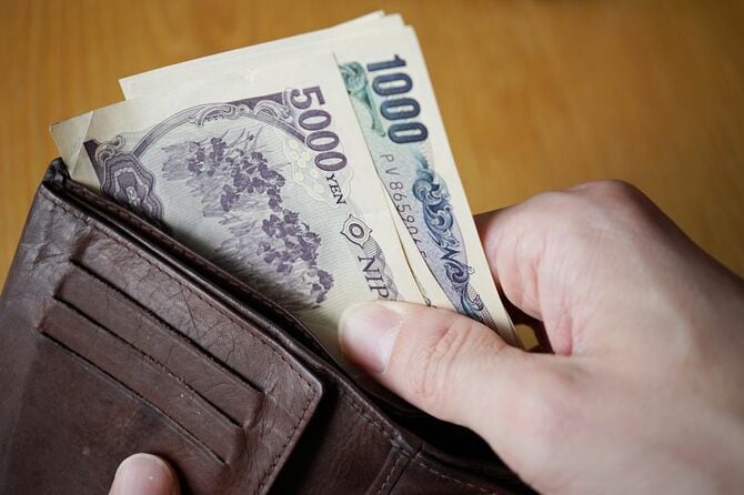 革の財布からお札を引き出す男性の手