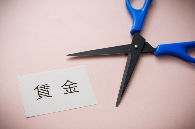 賃金と書かれたカードをカットしようとしているハサミ