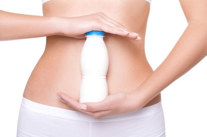 ヨーグルトの入ったボトルをお腹の前で持つ女性