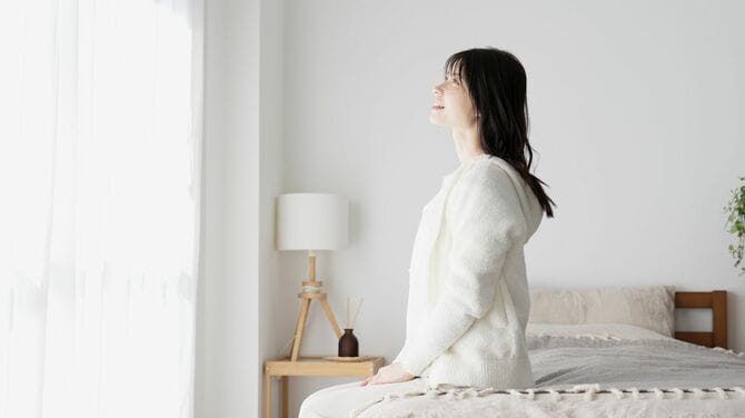 朝、窓の外を眺める女性