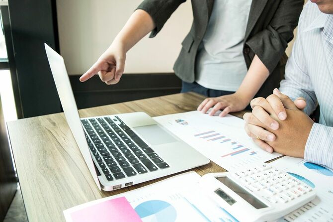 オフィスでパソコンを見ながら指摘するビジネスマン