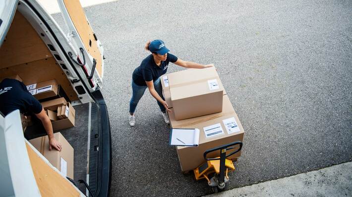 大きな段ボールに入った荷物を運ぶ配達員