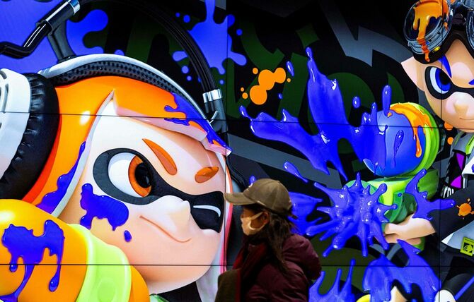 日本のゲーム大手、任天堂の店舗で、任天堂のゲーム「スプラトゥーン」のキャラクターが表示されたスクリーンの前を通るマスクを着けた人（2022年2月3日、東京都千代田区）