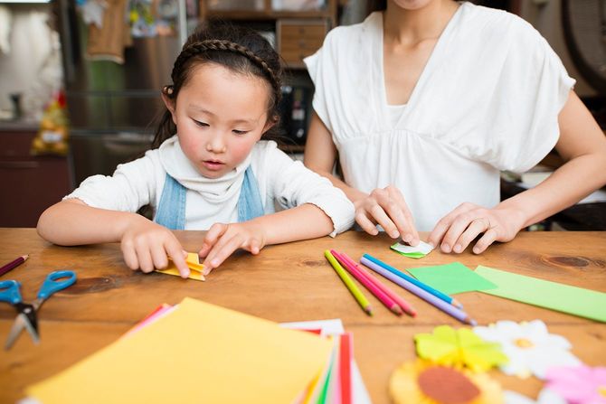 母と娘が折り紙で遊ぶ 