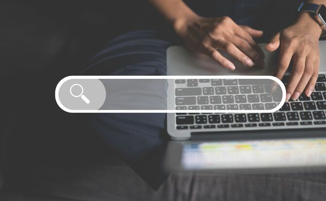 ラップトップで検索する男性の手元