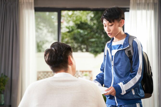 リュックを背負って、リビングで父親と話している少年