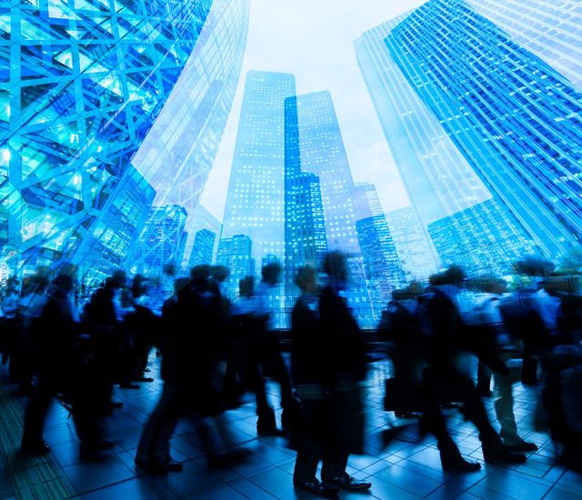 ラッシュアワー時にビル群の間を歩く人々