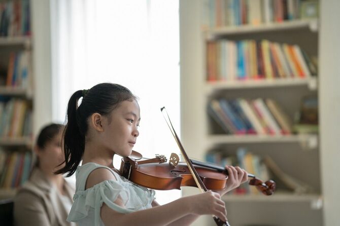 母親の前でバイオリンを演奏する女の子