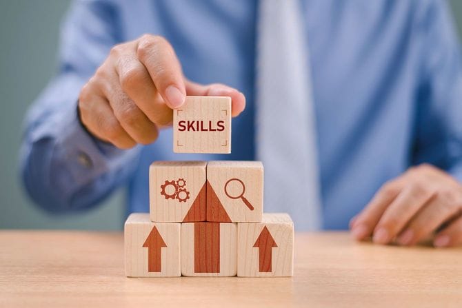 「SKILLS」と書かれた木製ブロックを積み上げる男性