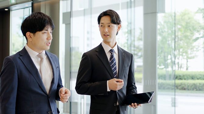 歩きながら話をする2人のビジネスパーソン