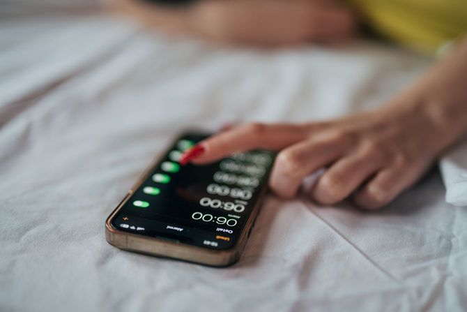 朝、携帯電話のアラームをスヌーズする人