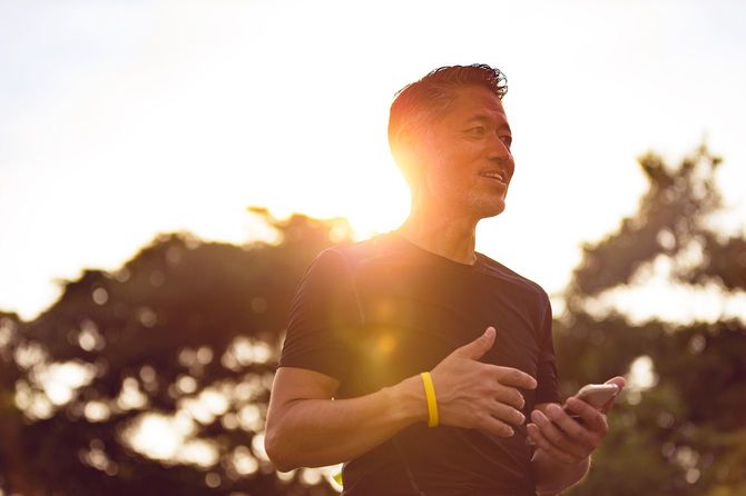 夕方のジョギング中にスマホを確認するシニア男性