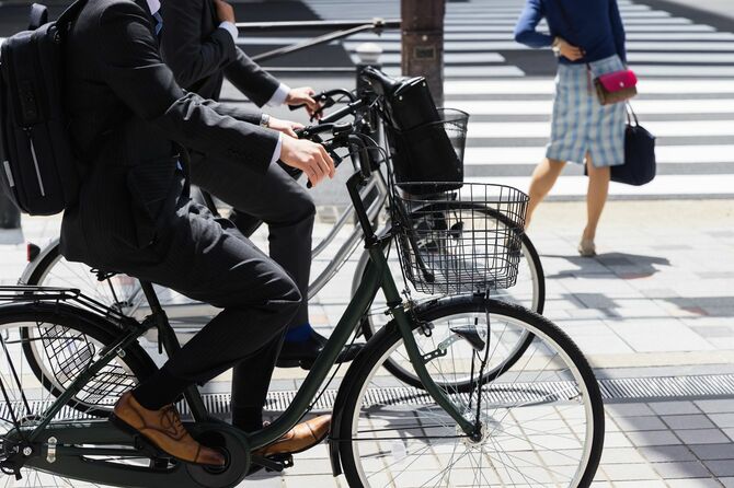 東京の歩道でビジネスマンの乗る自転車が並列して走っている