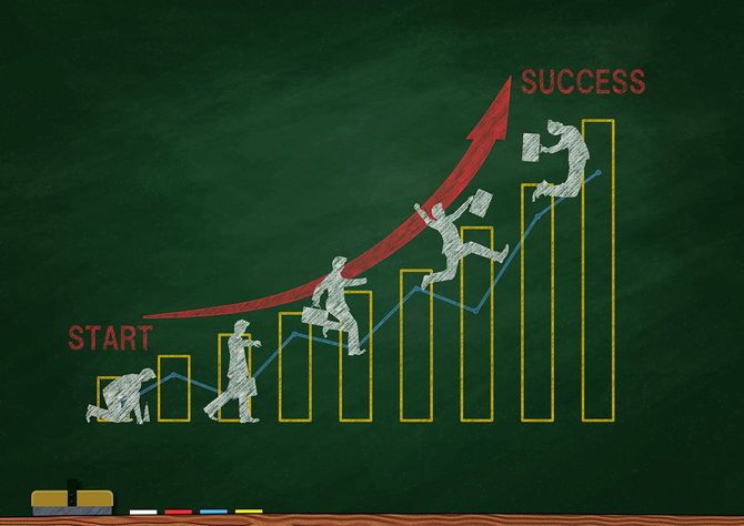 黒板に人物のジャンプする図で表現された右肩上がりのグラフ