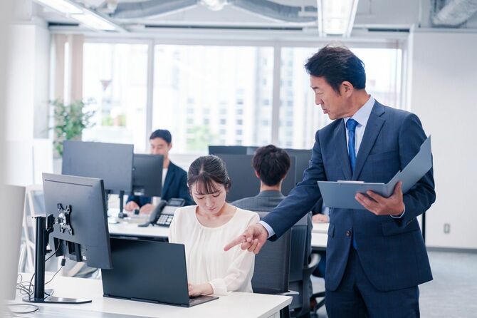 職場で若いスタッフを叱責する中年の上司