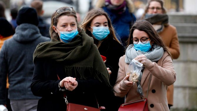 マスクを着用して歩く人々。ロンドンの中心、バッキンガム宮殿付近にて＝2020年3月15日