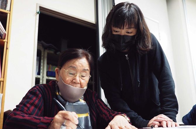 ハルモニに「平和」という文字を教えるフォトジャーナリストの安田菜津紀さん（右）。2021年4月、筆者撮影。