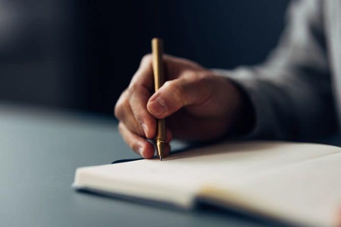 高級ペンでノートに手書きする手のクローズアップ