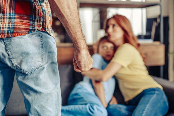 手前に拳を握りしめる男性、奥に怯える母と子