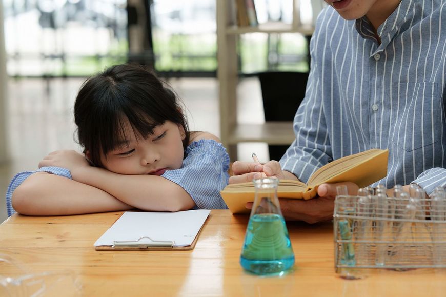科学の実験をしながら眠そうにしている子ども