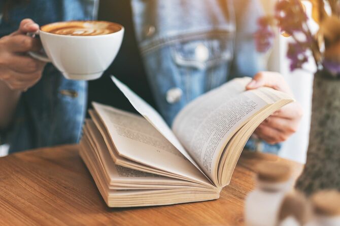 コーヒーを飲みながら本を読んでいる女性