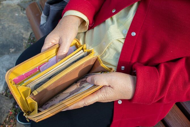 財布を開いて見せているシニア女性の手元