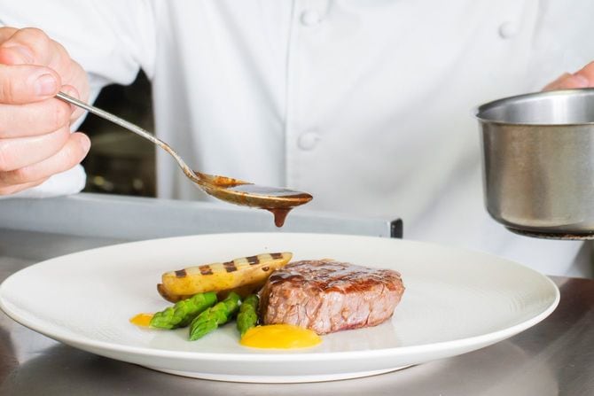高級ステーキに手づくりソースをかけるシェフ