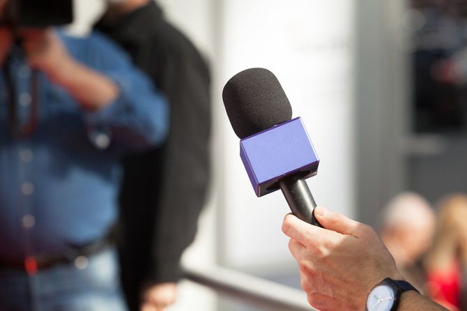 取材対象者にマイクを向けている記者