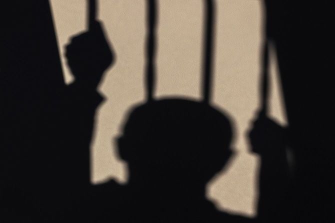 白い壁に映し出された独房の中の捕虜の影