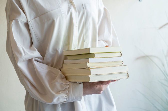 たくさんの本を持つ若い女性