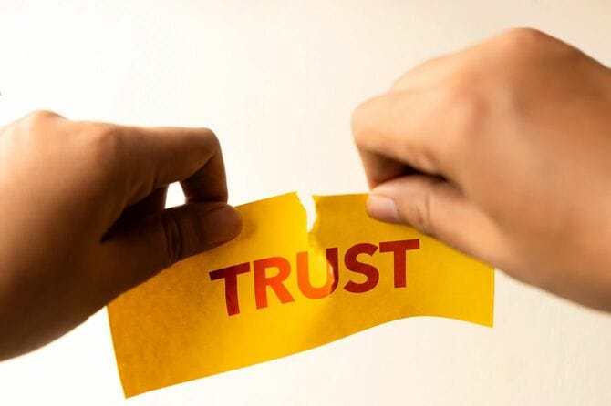 TRUSTと書かれた紙を破る手