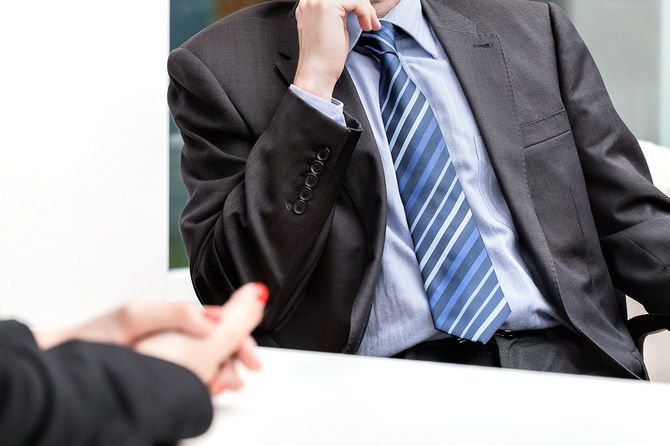 肘をついて会話を聞くビジネスマン