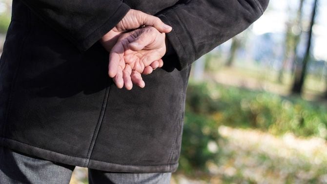 手を後ろで組むシニア男性