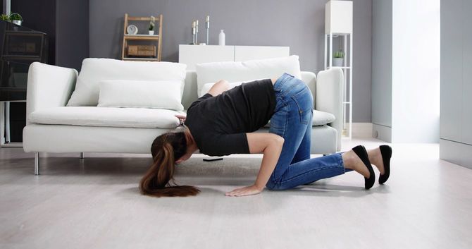 ソファーの下をのぞく女性