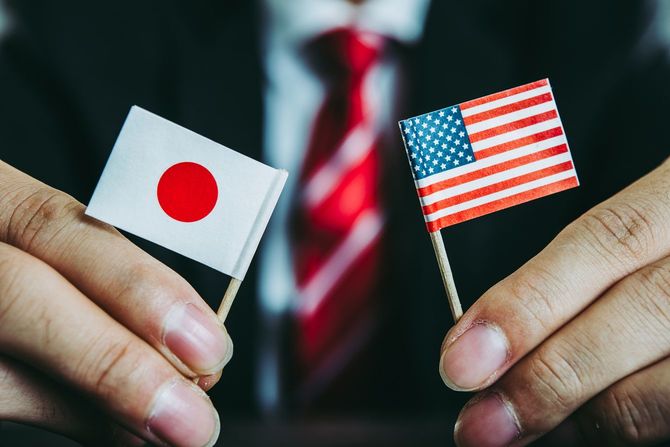 ミニチュアの日章旗と星条旗を手に持つ男性