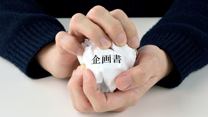 男性の手が荒々しく企画書を丸めている